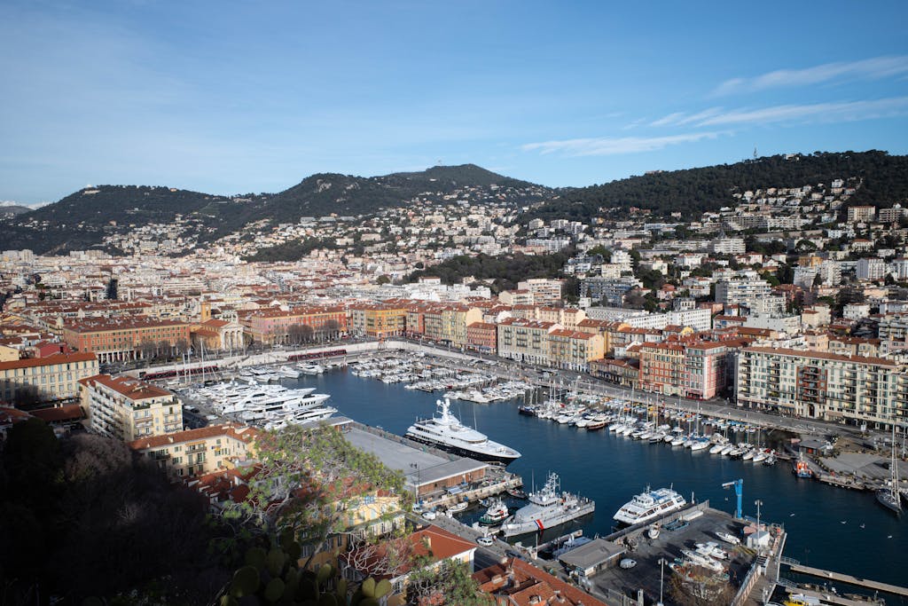 A picturesque view of the Nice harbor with yachts and historical buildings under a clear blue sky.