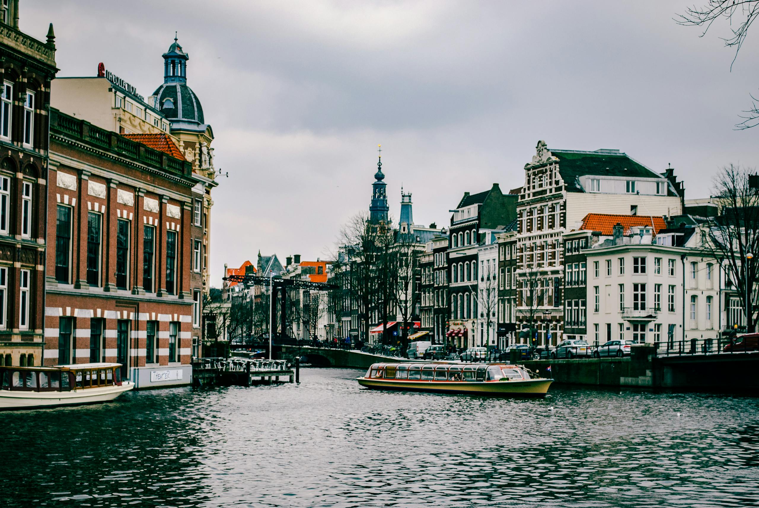 Charming canal scene in Amsterdam with historic architecture and a passing boat.